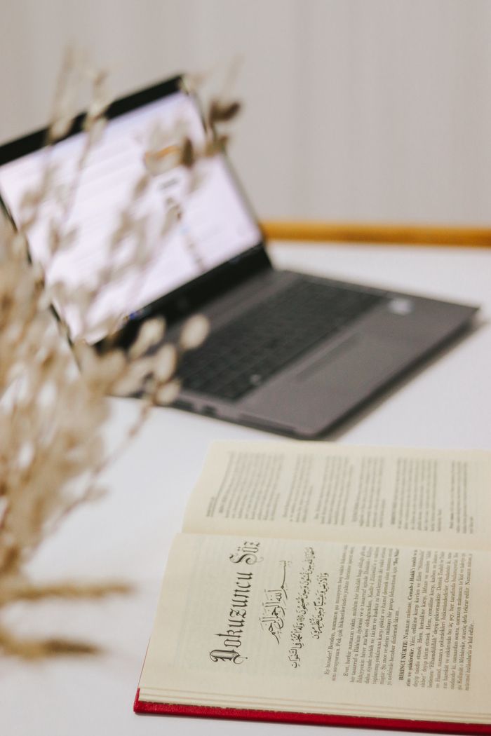 A serene minimalist workspace featuring an open book and laptop, perfect for studying or working.